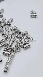 Silver metal hair beads with engraved swirl patterns for braids or locs on white background