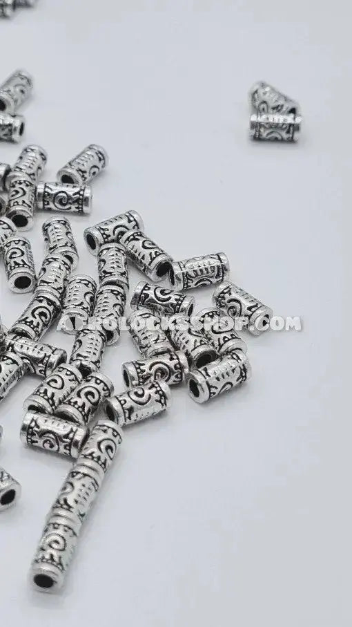 Silver metal hair beads with engraved swirl patterns for braids or locs on white background