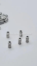 Silver-tone metal hair beads with engraved afro-inspired patterns for locs and braids on white background