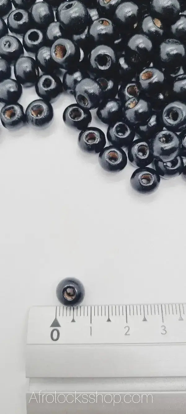 Small black wooden beads for afro hair accessories, shown with ruler for size reference