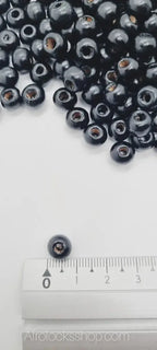 Small black wooden beads for afro hair accessories, shown with ruler for size reference