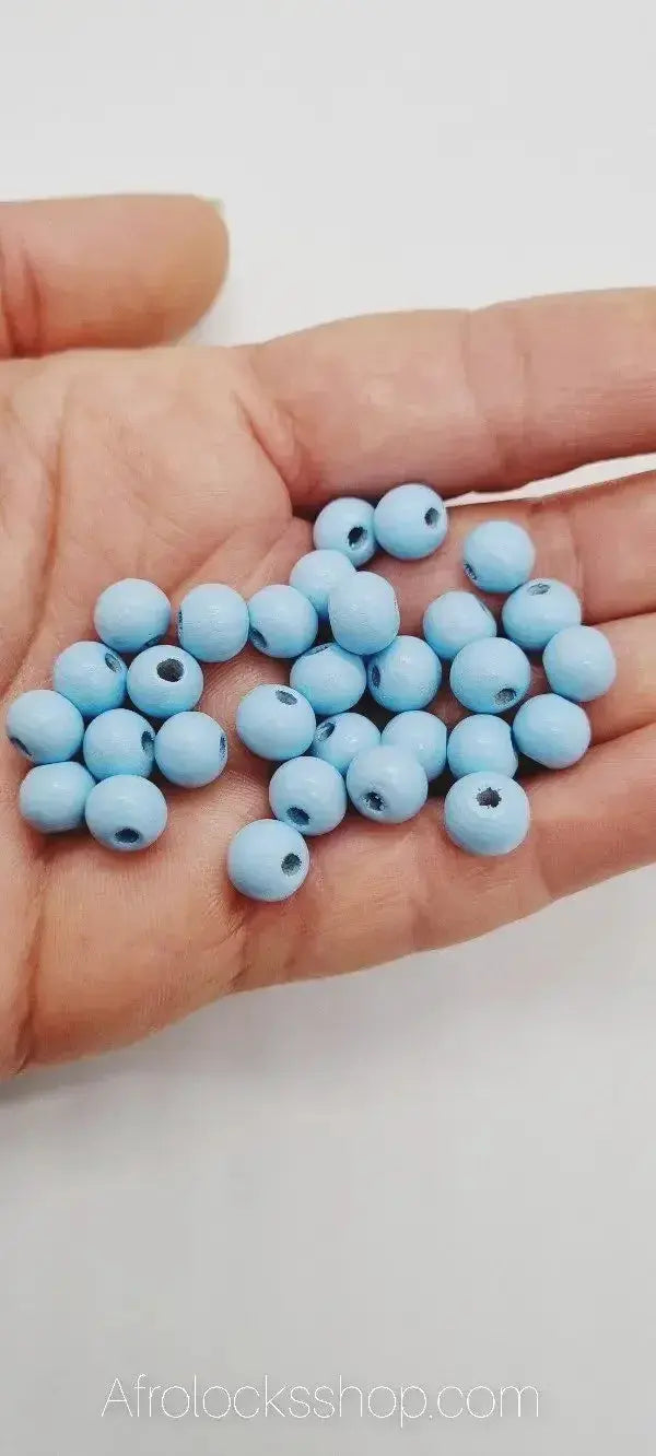 Hand holding multiple light blue wooden beads for hair accessories or jewelry making