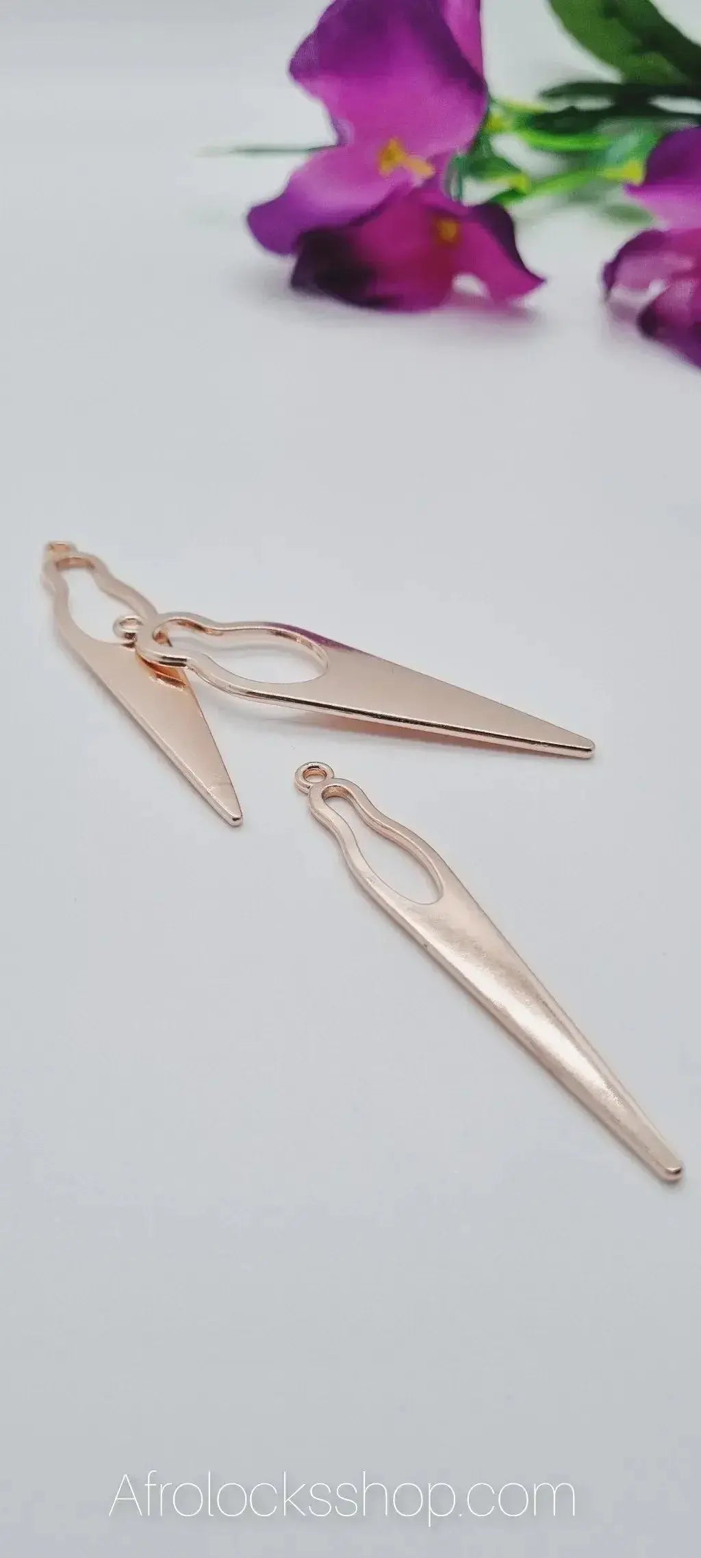 Gold-tone geometric earrings for locs on white background with purple flowers