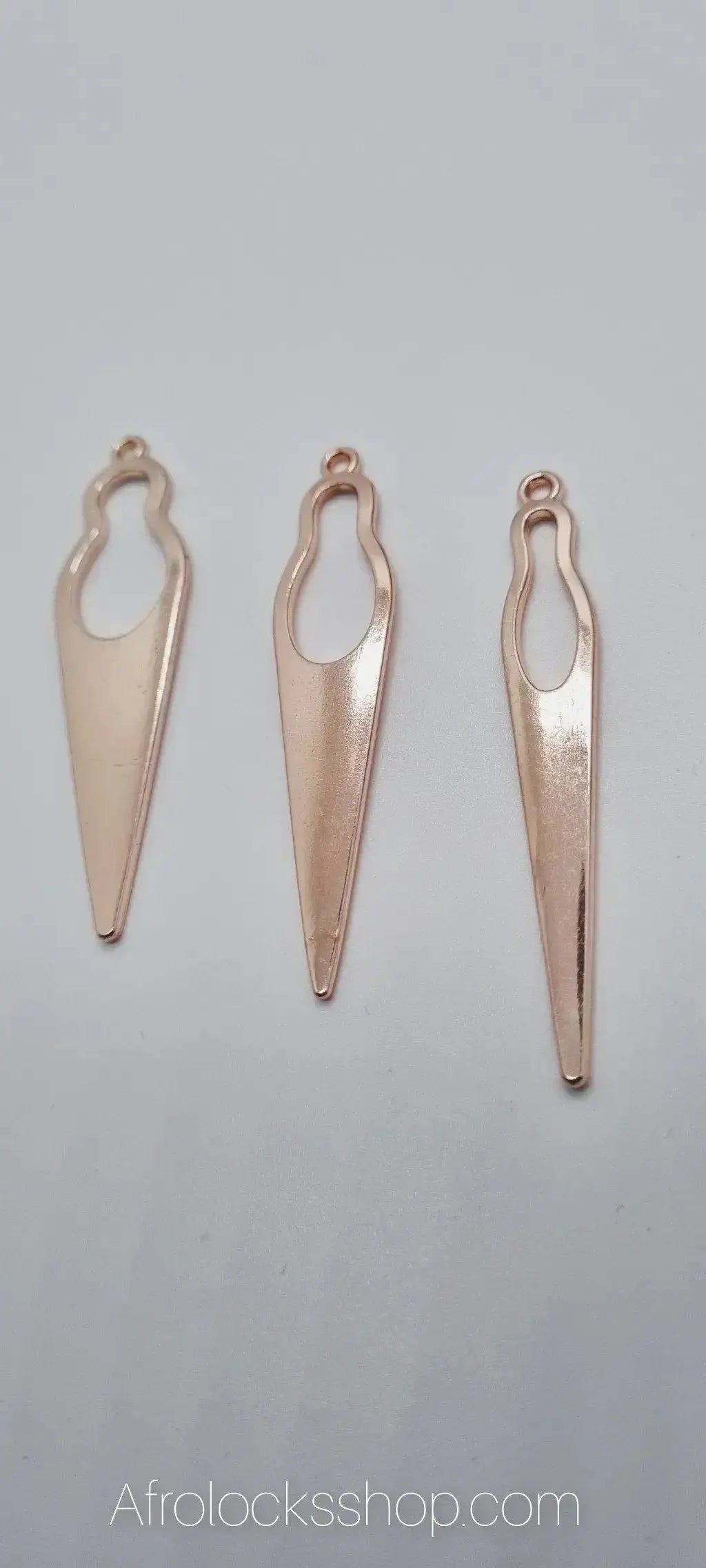 Three gold-tone metal African woman silhouette pendants for handmade afro jewelry on white background