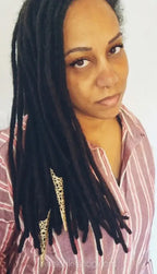 Woman with long afro locks wearing gold filigree hair jewelry, striped shirt, close-up.