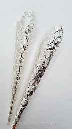 Two silver filigree hair accessories for locks and braids on white background