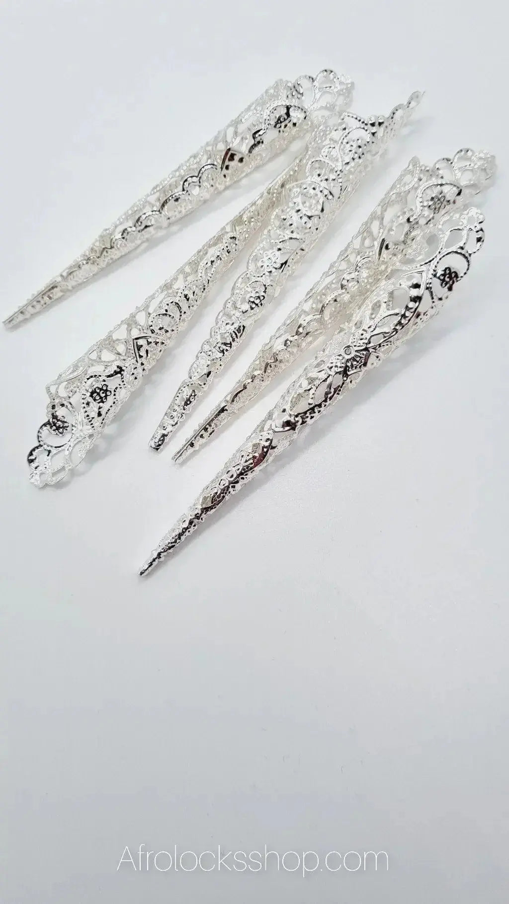 Set of ornate silver hair cuffs for dreadlocks or braids on white background