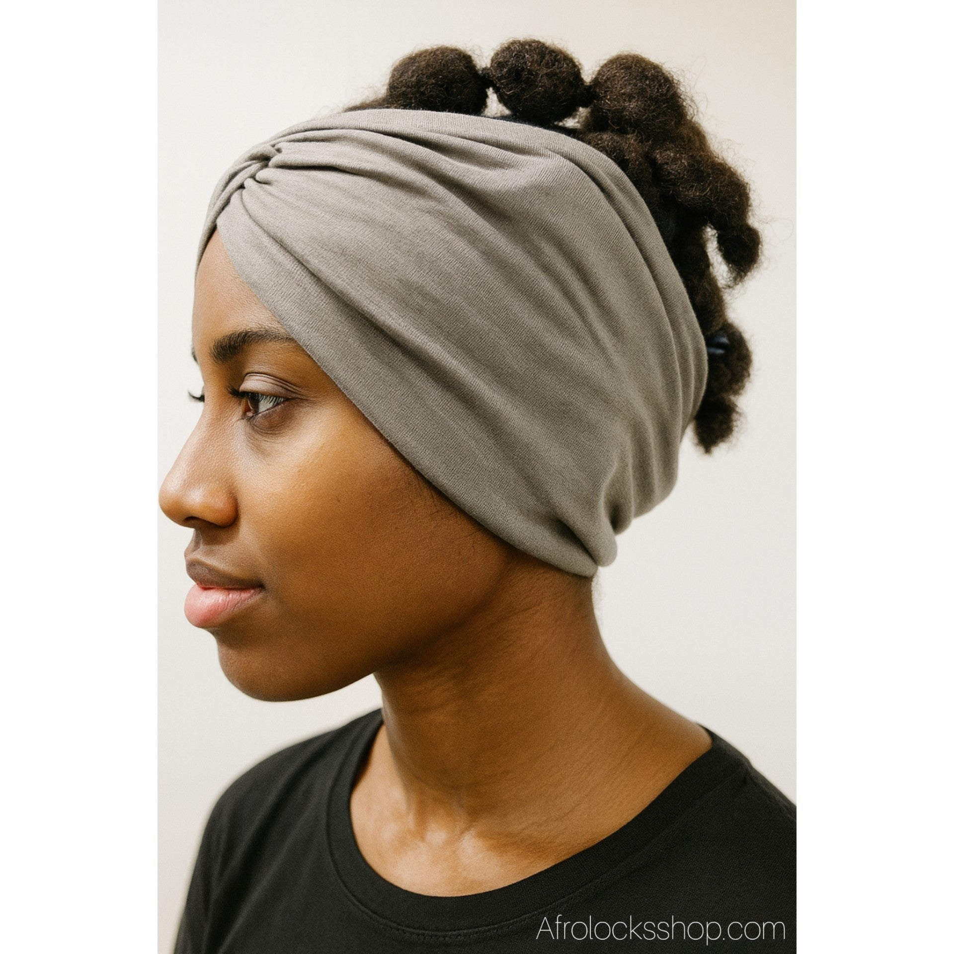 Serre-tête large gris porté sur cheveux afro volumineux, vue de profil.