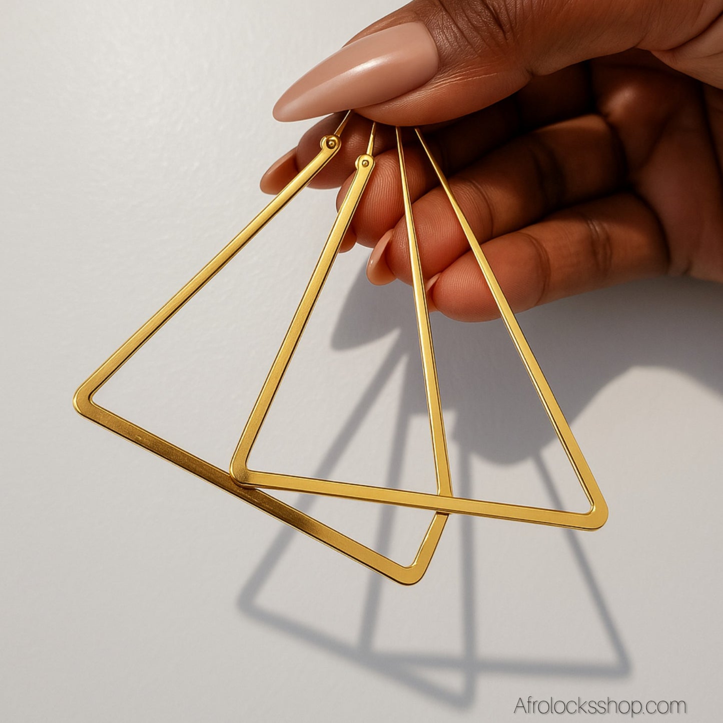 vue de pres d'une paire de boucles d'oreilles dorees triangle