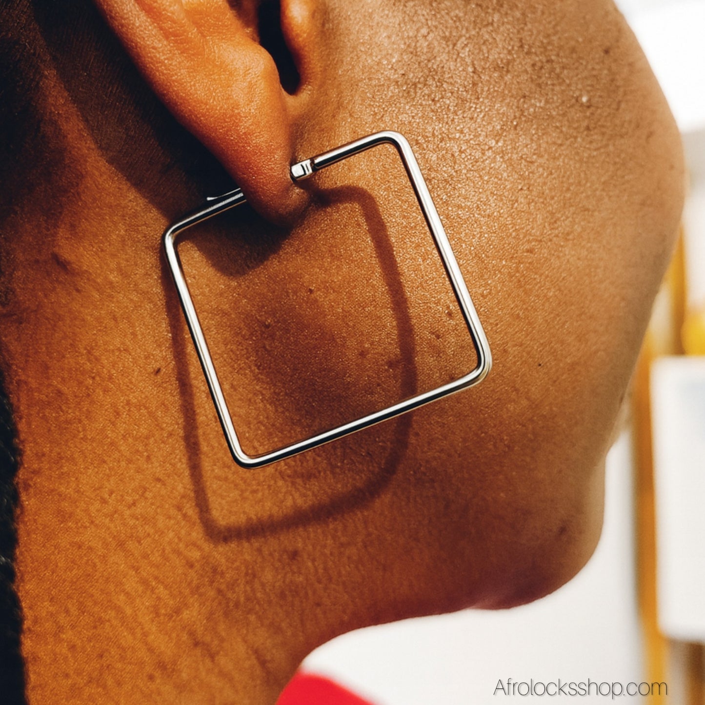 profil de femme qui porte une boucle d'oreille forme carre