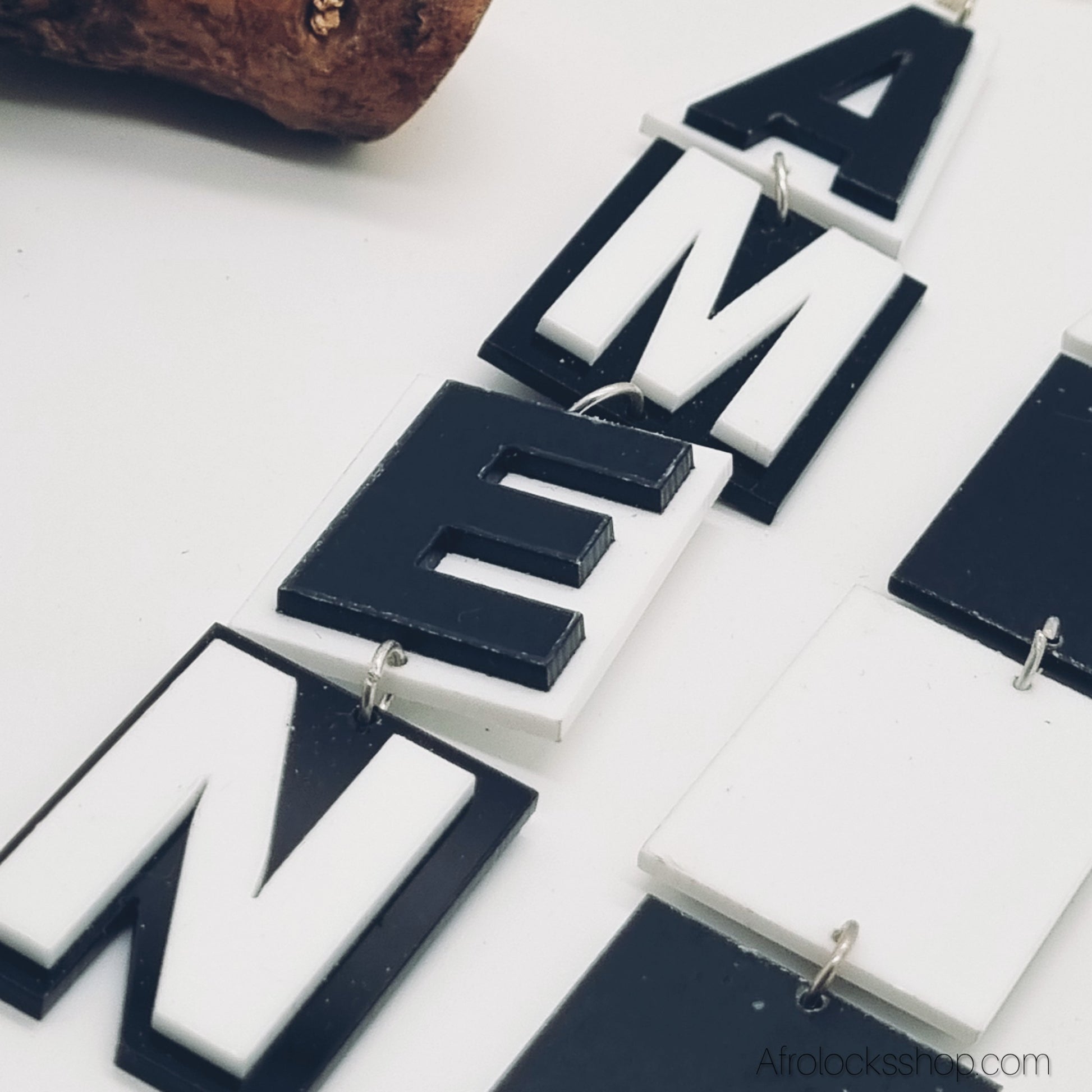 boucles d'oreilles tres grandes avec des lettres ou se lit le mot Amen