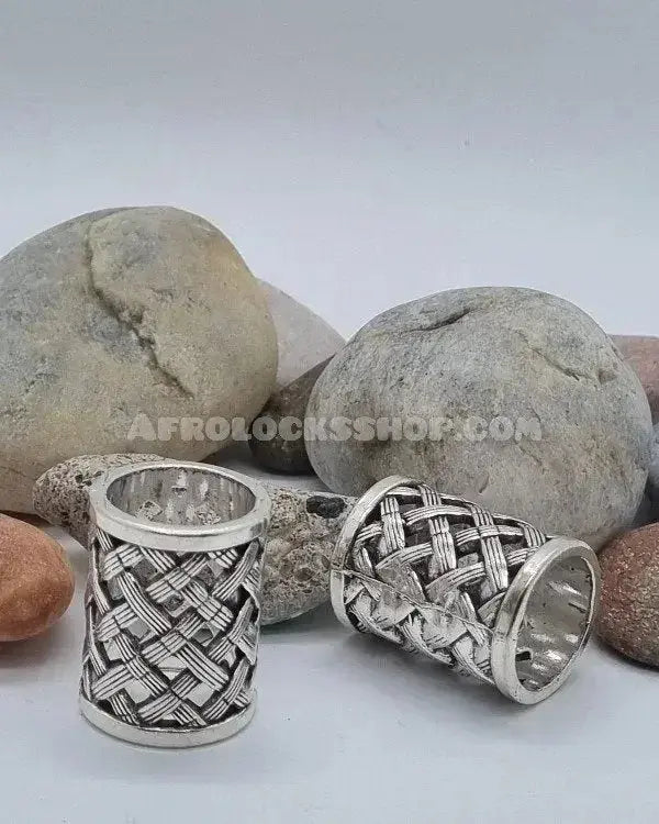Silver hair cuffs with woven pattern for locs or braids, displayed on natural stones