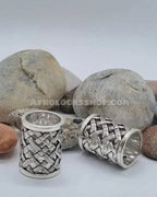 Silver hair cuffs with woven pattern for locs or braids, displayed on natural stones