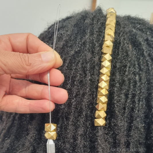 perles dorees vues posees sur des microlocks comme un bijou avec un enfileur de perles