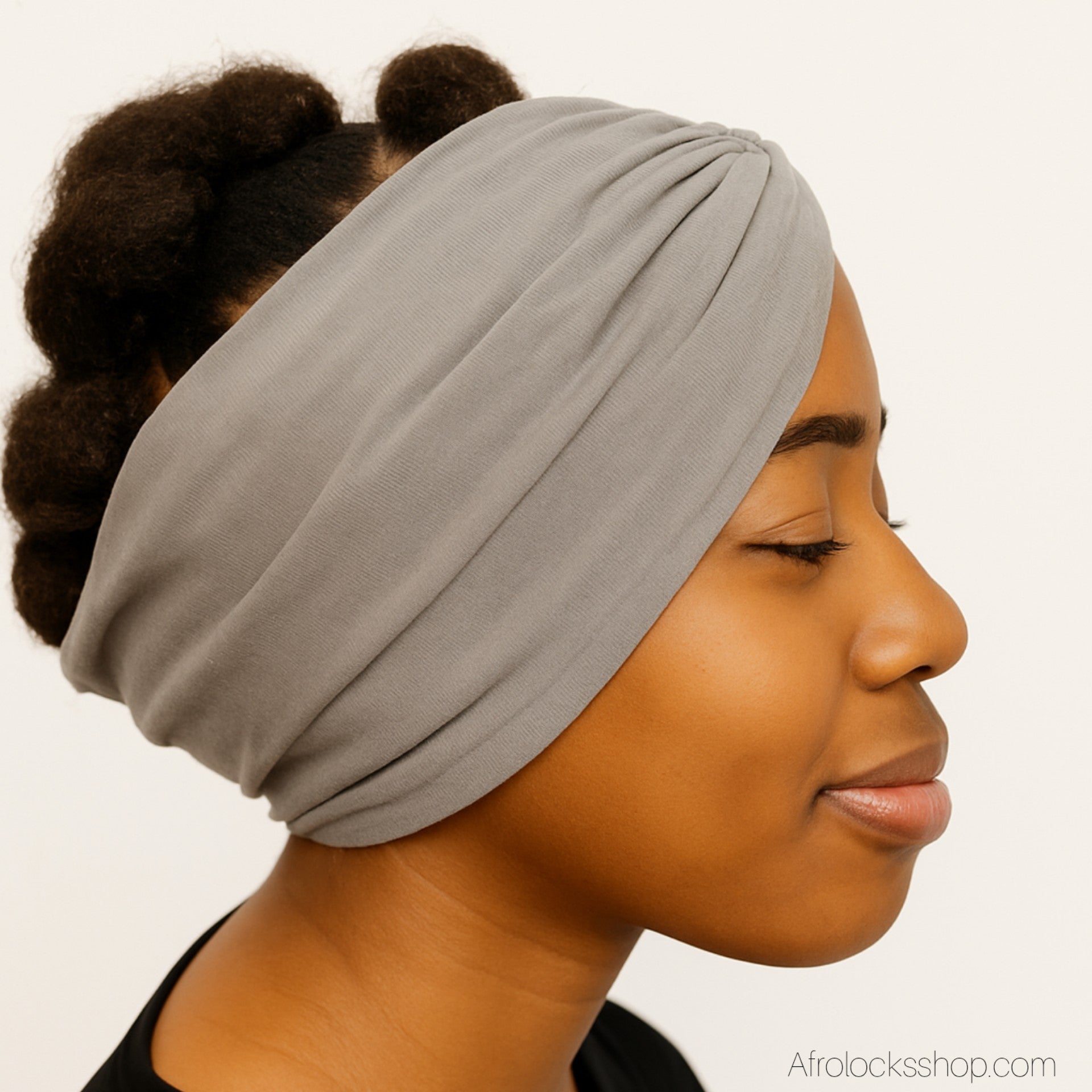 Serre-tête large gris porté de profil sur cheveux crépus.